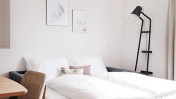 Un dormitorio minimalista con cama, mesita de noche, silla y lámpara de pie.