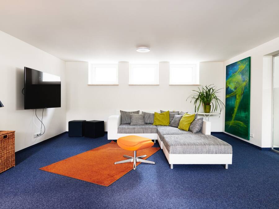 Een moderne woonkamer met een hoekbank, een flatscreen televisie, een salontafel en een groot abstract schilderij.