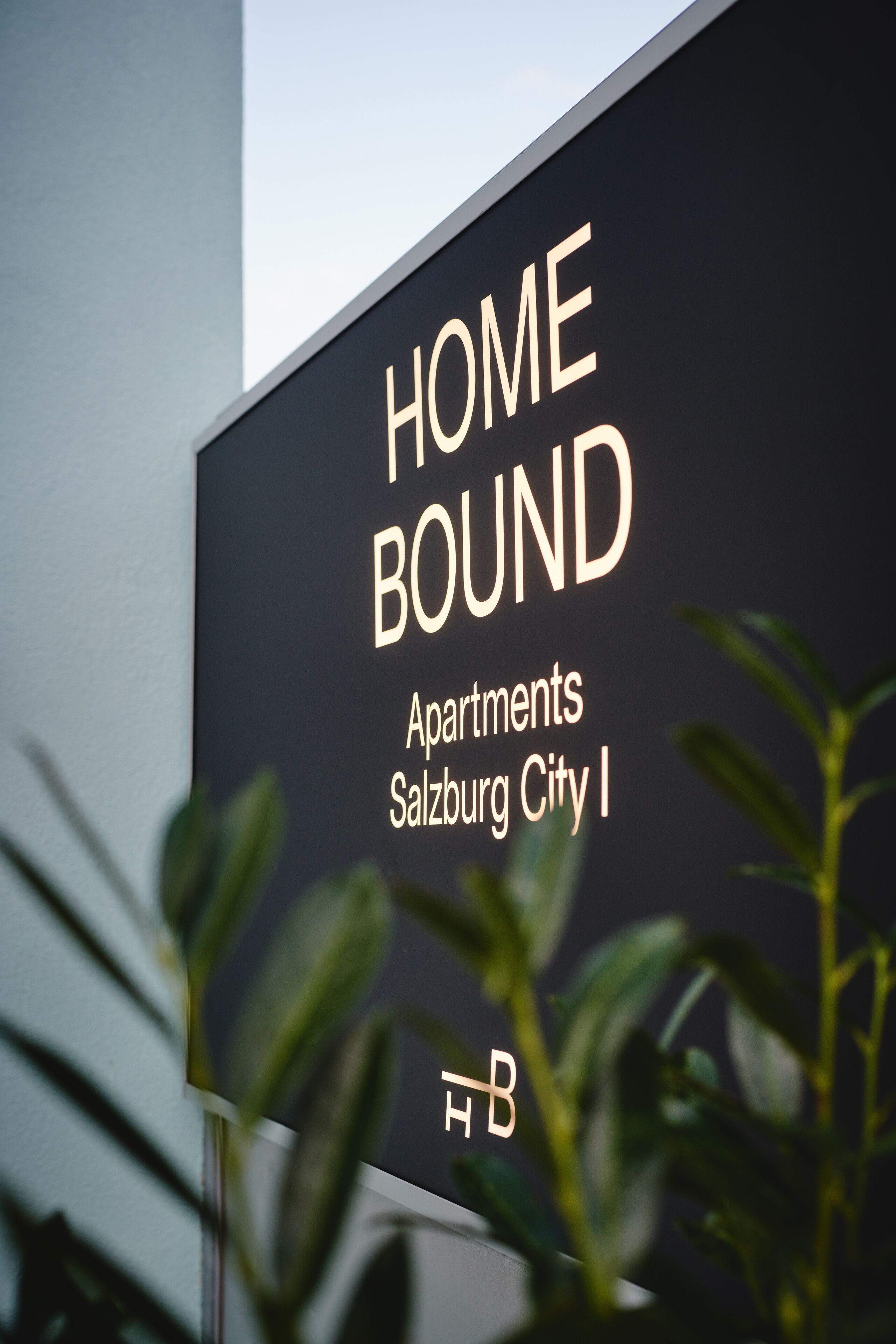 Une enseigne pour « HOME BOUND Apartments Salzburg City I », avec un logo en bas.