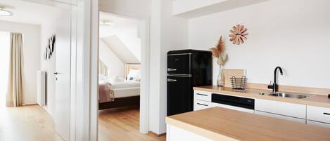 Een moderne keuken met een houten aanrecht, een zwarte koelkast en een spoelbak.