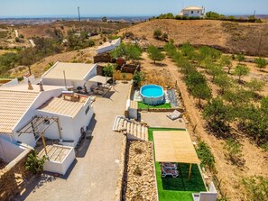 A residential area with white houses, a swimming pool, and a green lawn.
