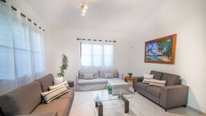 Ein Wohnzimmer mit zwei Sofas, einem Glastisch und einem Gemälde an der Wand.