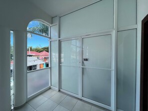 A room with a large window, a sliding door with a number plate, and a tiled floor.