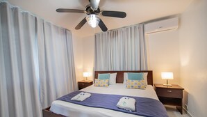 A hotel room with a bed, two bedside tables, a ceiling fan, and an air conditioning unit. - 7br Massive Villa In Sosúa - 2mins From Nightlife! (Sosúa)