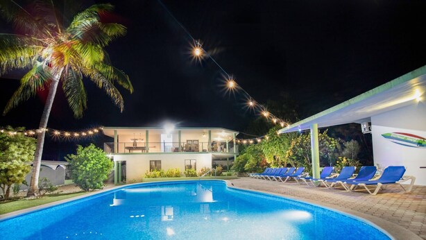 A swimming pool with lounge chairs, palm trees, and a building with a balcony. - 7br Massive Villa In Sosúa - 2mins From Nightlife! (Sosúa)