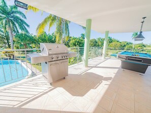 Um pátio ao ar livre com churrasqueira, piscina e mesa de bilhar.