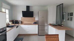 Eine moderne Küche mit weißen Schränken, einem Edelstahl-Kühlschrank, einem Einbauofen und einer Holzarbeitsplatte.