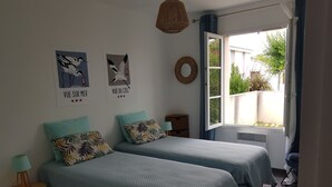 Ein Schlafzimmer mit zwei Betten, einem Fenster mit Aussicht und Wandbildern.