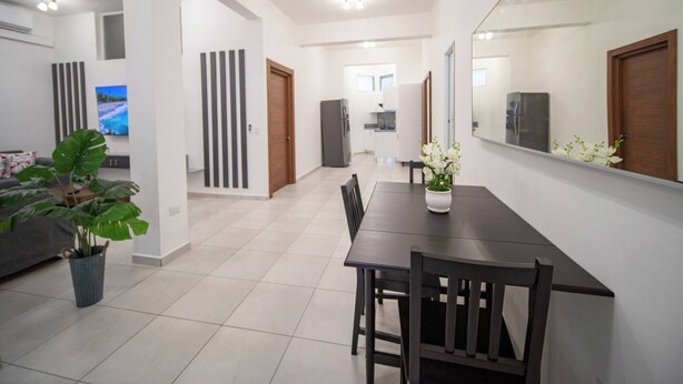 A modern living room with a dining area, a large mirror, and a potted plant. - Cozy 1 Bedroom Apartment in Heart of Sosúa (Sosúa)