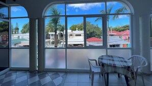 A room with large windows, a checkered table, and a tiled floor. - Cozy 1 Bedroom Apartment in Heart of Sosúa (Sosúa)