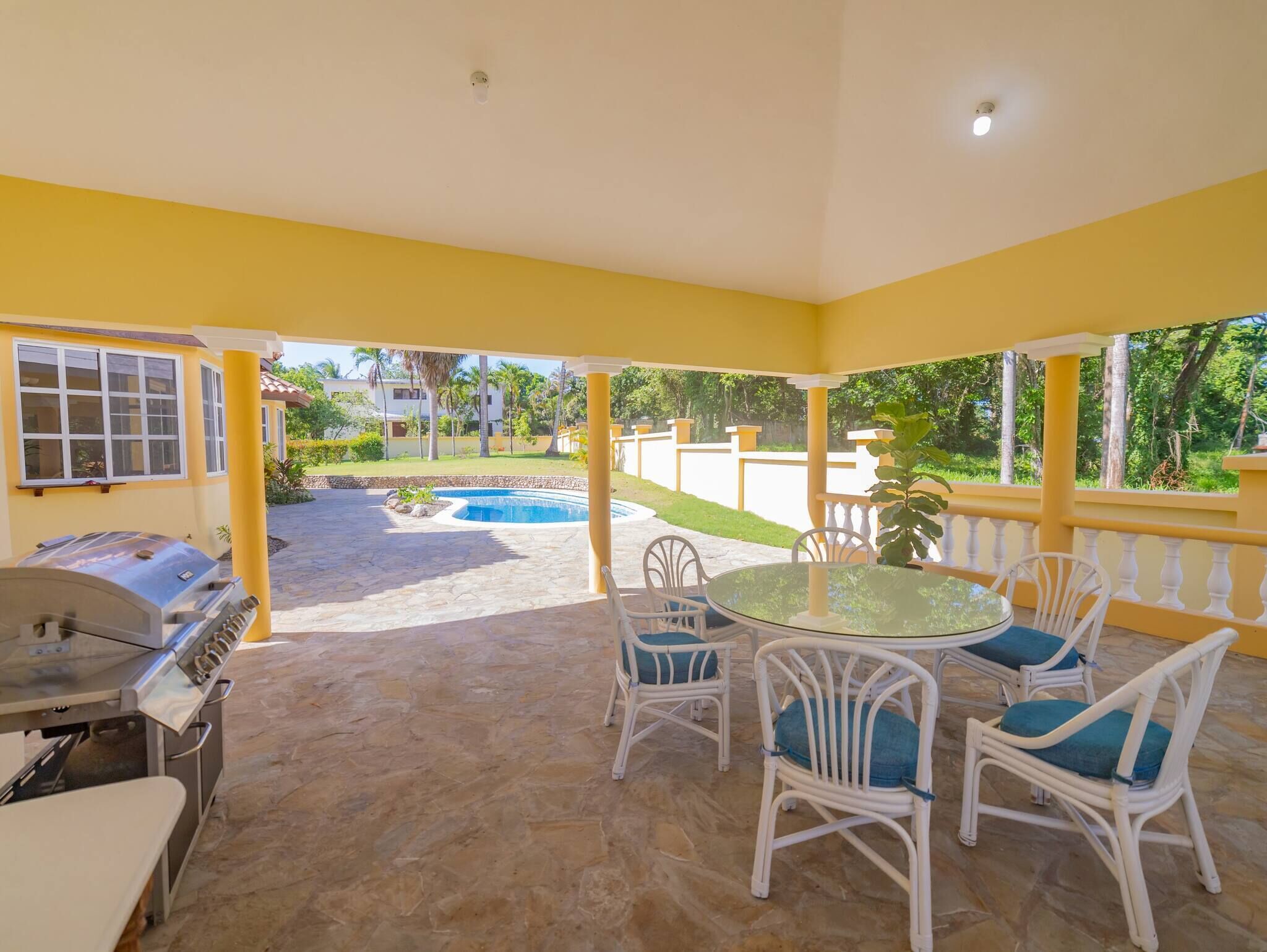 Eine überdachte Terrasse mit Grill, Sitzgelegenheiten im Freien und einem Swimmingpool.