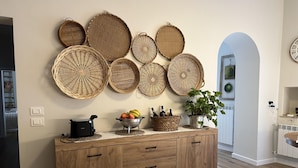 A wooden cabinet with drawers, a fruit bowl, and a kettle on top. - HARMONY Residence (Spello)