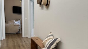 A hallway with a wooden bench, a fur throw, and a coat rack with hats. - HARMONY Residence (Spello)