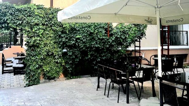 Un área de estar al aire libre con mesas y sillas, un toldo blanco y un edificio con un letrero que dice "Casa Lema Bay".