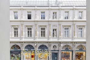 A classical building with multiple windows and statues, featuring a coffee shop and a restaurant with outdoor seating.