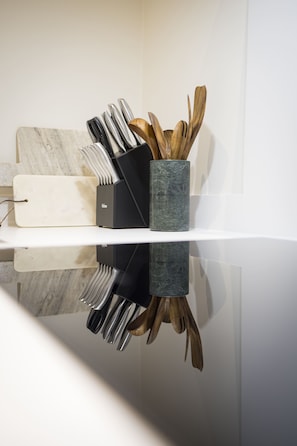 A kitchen counter with a knife block, wooden utensils, and a cutting board.