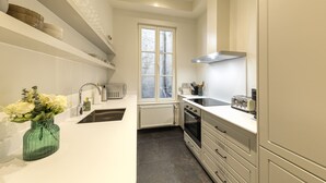 Eine moderne Küche mit weißen Schränken, einem eingebauten Backofen, einem Fenster und einer Vase mit Blumen auf der Arbeitsfläche.
