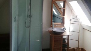Ein Badezimmer mit einer Duschkabine, einem Holzmöbelkorpus inklusive Waschbecken und einem Oberlicht.
