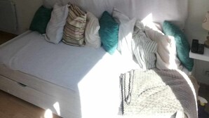 Ein Bett mit weißem Kopfteil und mehreren Kissen, darunter grüne und gestreifte.