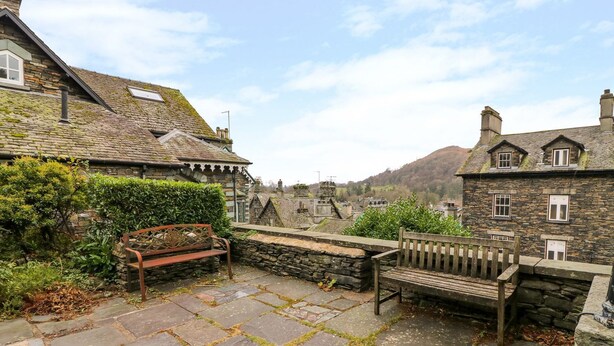 A stone-paved courtyard with benches, stone walls, and traditional stone buildings with pitched roofs. - La'l Tethera (Ambleside)