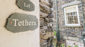 A stone wall with two signs reading "La'l" and "Tethera". - La'l Tethera (Ambleside)
