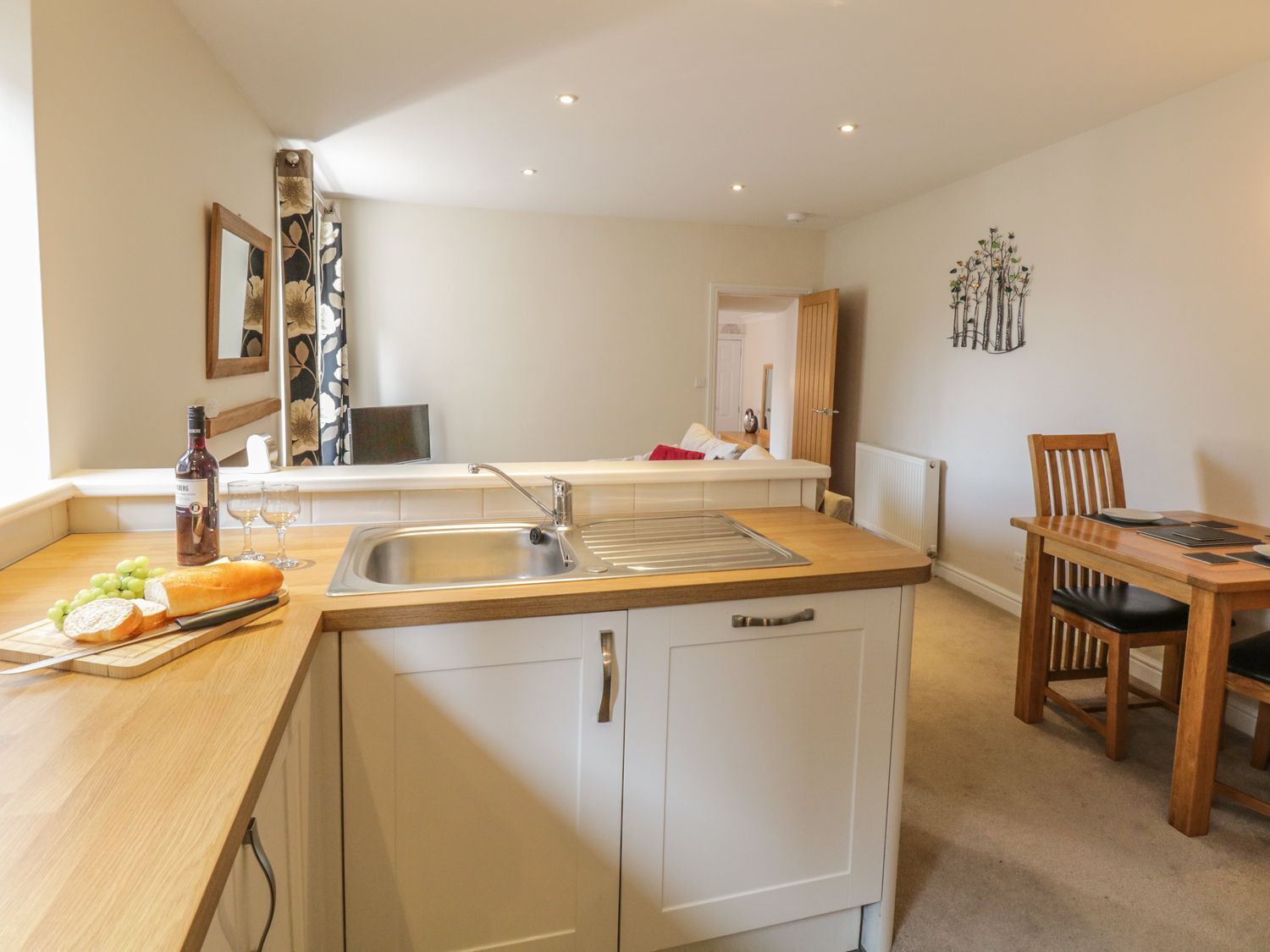 A compact kitchen with a sink, a dining table, and a chair.