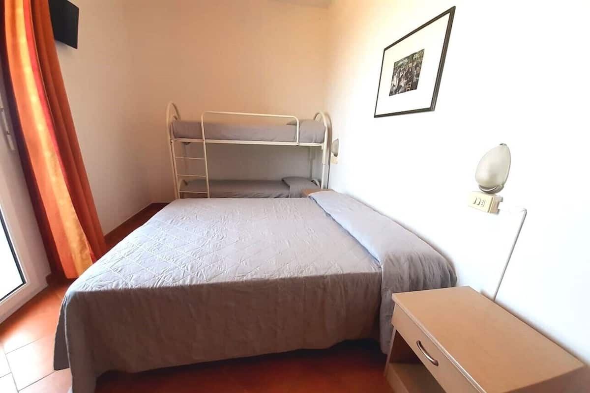 Una habitación con literas, una mesita de noche, una lámpara y un cuadro en la pared.