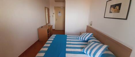 A bedroom with a bed, a desk, and a chair.