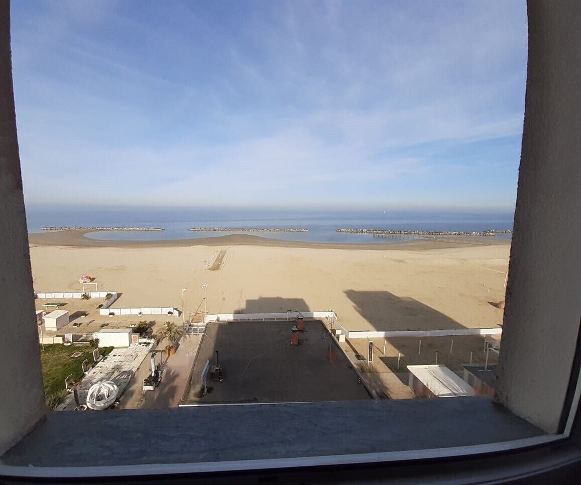A view from a window overlooking a beach with a clear sky.