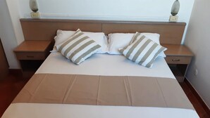 A neatly made bed with striped pillows and a plain white bedspread. - Hotel Salsedine  (Rimini)