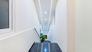 A modern, well-lit hallway with a staircase leading to a landing. - Treebo Rakshitha (Chennai)