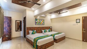 A hotel room with two beds, a ceiling fan, an air conditioning unit, and a wooden door. - Treebo Rakshitha (Chennai)