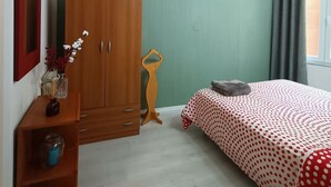 A bedroom with a bed, a wardrobe, a small table with a vase, and a window with curtains. - Super cozy studio in Pomposa, in the heart of the city (Modena)