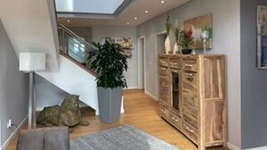 Moderni sisustus, jossa on portaikko, suuri ruukussa oleva kasvi ja puinen kaappi.