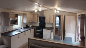 A compact kitchen with a microwave, stove, and sink, and a small dining area with a table and chair.