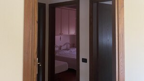 A doorway leading to a bedroom with a bed, a bedside table, and a wardrobe. - "COTTAGE ULIVO" 
Codice Identificativo: 046017LTN2254 (Lucca)