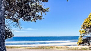 Une route côtière offrant une vue dégagée sur l’océan et donnant accès à une plage de sable.