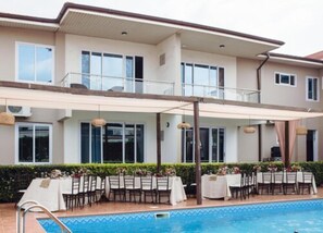 A two-story building with a covered outdoor dining area and a swimming pool. - Cromer Serviced Apartments (Accra)