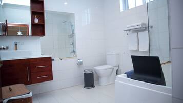 A modern bathroom with a white sink, wooden vanity, glass shower enclosure, white toilet, and a bathtub with a towel rack.