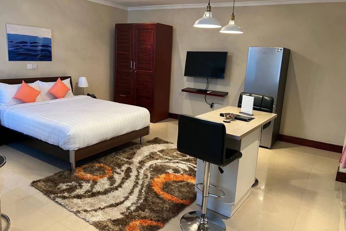 A hotel room with a bed, a desk, a TV, a wardrobe, and a bathroom.