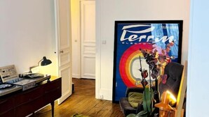 Una sala de estar con piso de madera, un sofá, una mesa de centro, un televisor y un cuadro en la pared.