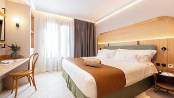 A modern hotel room with a large bed, a desk, and a chair.