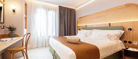 A modern hotel room with a large bed, a desk, and a chair.