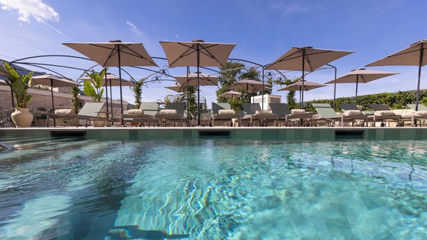 Ein klares Schwimmbecken mit Liegestühlen und Sonnenschirmen.