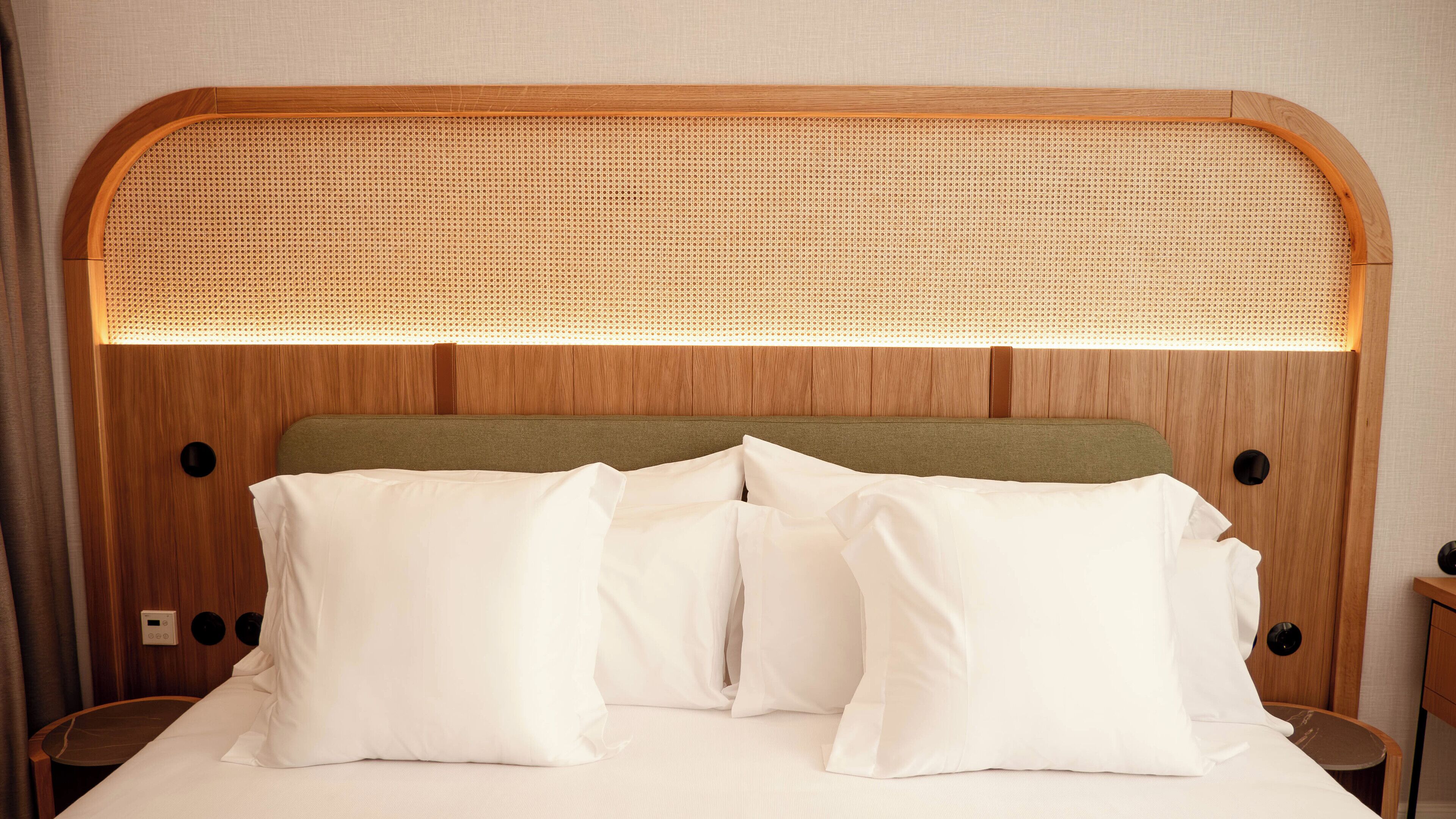 Una cama con cabecera de madera, dos almohadas y una mesita de noche.