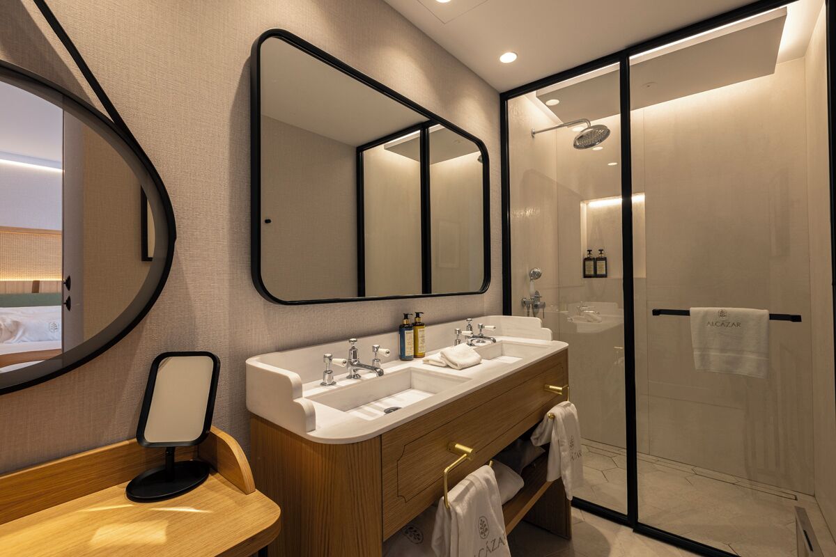 A modern bathroom with a double sink vanity, a large mirror, and a glass-enclosed shower.