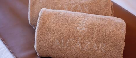 Two rolled towels with the text "ALCazar" on a brown leather surface.