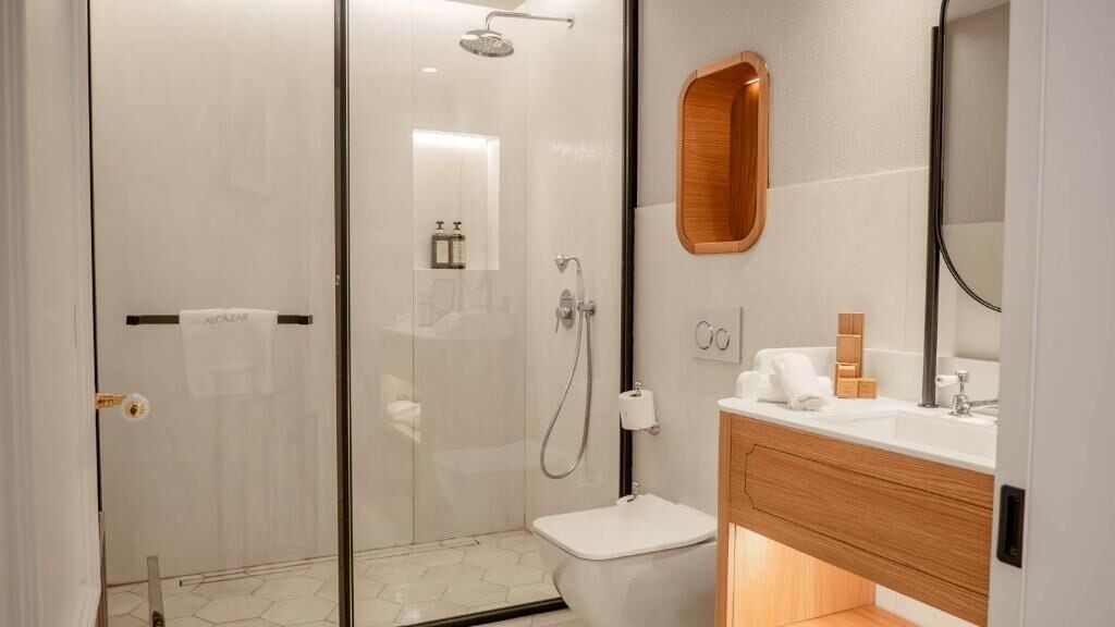 Un baño moderno con cabina de ducha de vidrio, inodoro y tocador con espejo.