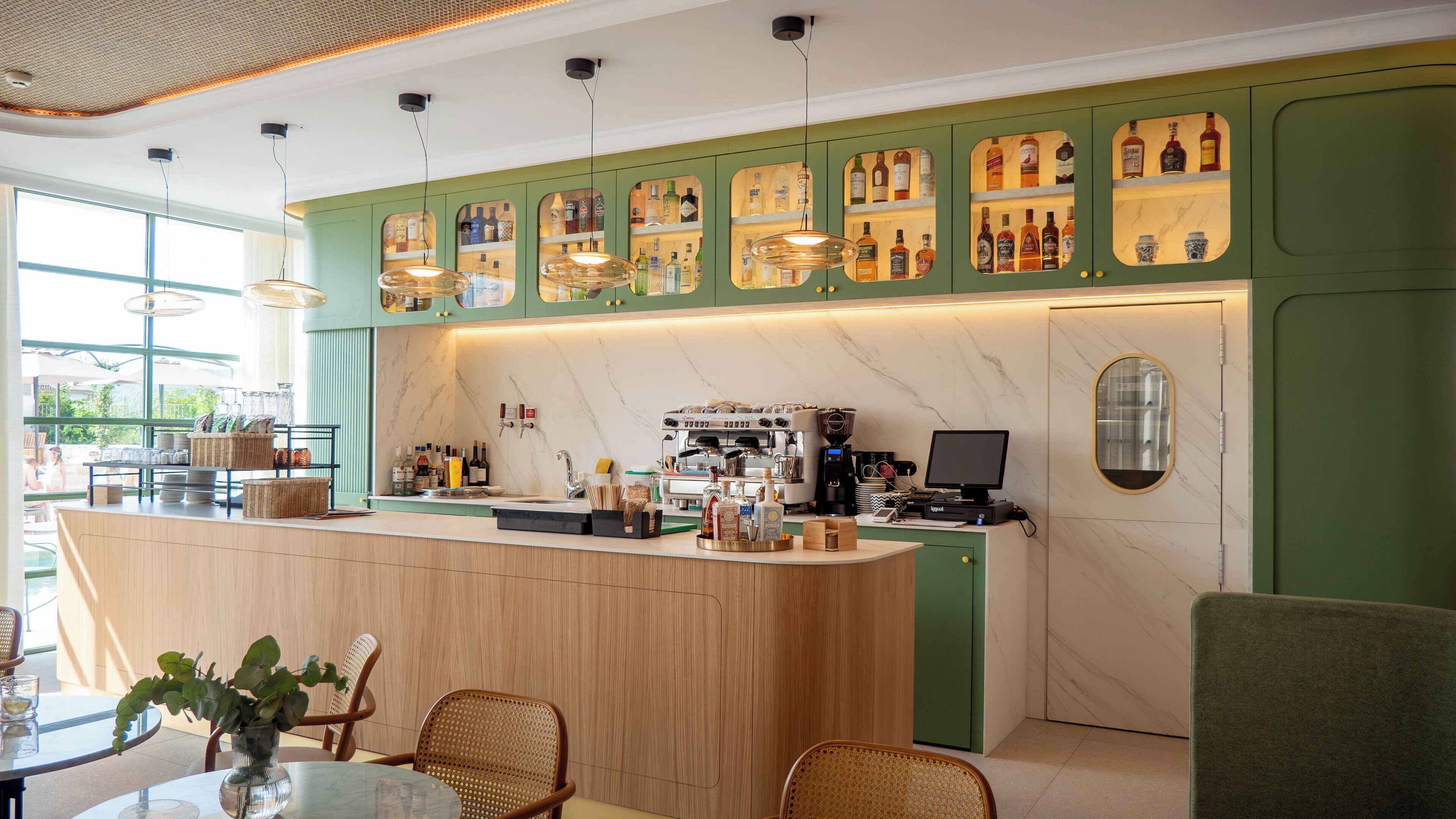 Un área de bar moderna con mostrador de madera, una máquina de café y varias botellas.