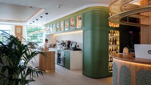 Eine moderne Bar mit grünen Schränken, einer Kaffeemaschine und einem Laptop auf der Arbeitsfläche.